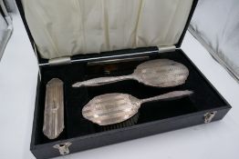 A silver engine turned dressing table set hallmarked W I Broadway and Co., 1972-1974. Cased, with tw