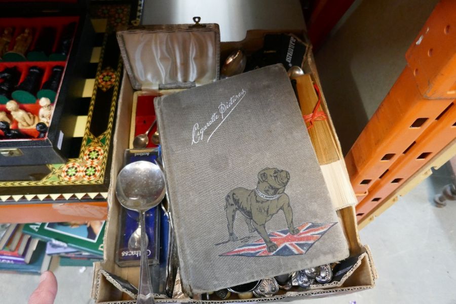 A box of silver plated cutlery and book cigarette cards