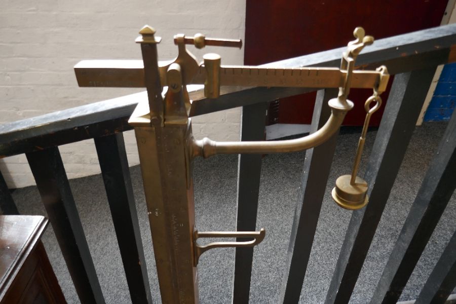 A set of brass and oak stand on weighing scales with adjustable brass measuring stick, by W & T Aver