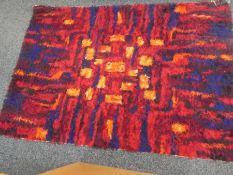 A 1970s Axminster rug having red, orange and blue colouring