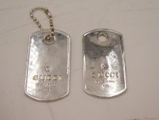 A pair of luggage tags stamped with Gucci, made in Italy,