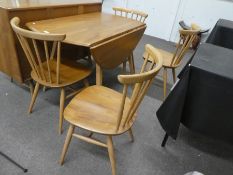 Ercol; an elm two flap kitchen table and a set of four stick back chairs