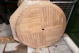 Two octagonal teak garden table tops and one other circular example