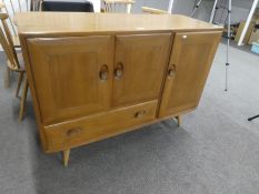 Ercol; an elm sideboard having cupboards and one drawer on turned legs, 114cms