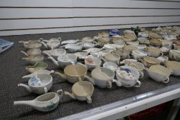 A large collection of vintage hospital feeding cups, ceramic and wooden, some A/F