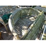 A weathered teak garden bench having bow shaped back
