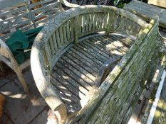 A weathered teak garden bench having bow shaped back