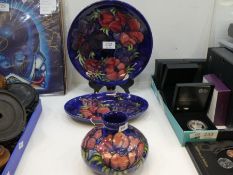 A Moorcroft blue squat base, decorated flowers, a similar oval dish and a circular plate