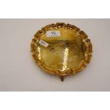 A silver gilt tray of circular form standing on three feet. Decorative, raised border. Engraved on t