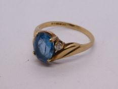 Pretty 9ct yellow gold crossover design ring with central oval blue topaz and single diamond, marked