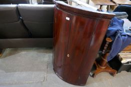 A Georgian mahogany bow fronted hanging corner cupboard