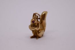 A 9ct yellow gold figural squirrel and charm inset with ruby eyes, marked GJ Ltd, 375, approx 1.5cm.