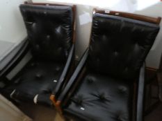 A pair of 1970s armchairs having faux black leather upholstery