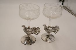 A pair of white metal glasses having a cockerel design stem on a circular base. Highly detailed and