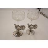 A pair of white metal glasses having a cockerel design stem on a circular base. Highly detailed and