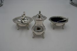 A silver cruet set by William Comyns and Sons Ltd comprising two large salts, with Bristol blue inse