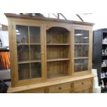 A modern pine kitchen dresser having pair of glazed doors with drawers and cupboards below
