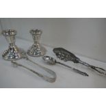 A pair of small silver candlesticks hallmarked Birmingham 1983 Bishton's Ltd. Silver tongs by Mappin