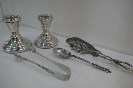 A pair of small silver candlesticks hallmarked Birmingham 1983 Bishton's Ltd. Silver tongs by Mappin