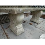 A reconstituted garden bench on pedestal supports
