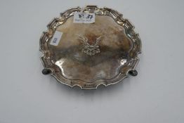 A small, heavy salver of circular form, on three feet and having scalloped design rim. Central engra