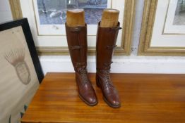A pair of brown leather military boots having three shin straps above laces with stretchers by Craig