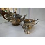 A silver tea service comprising of a large tea pot with embossed design rim, a milk jug and two hand