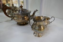 A silver tea service comprising of a large tea pot with embossed design rim, a milk jug and two hand