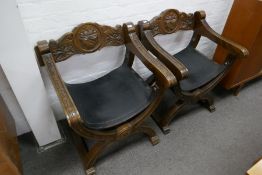 A pair of stained beech Spanish style throne chairs having black leather seats, with carved decorati