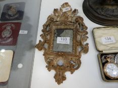 A small 18th Century carved wooden mirror of small proportions decorated leaves and scrolls, 26cm