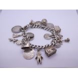 Silver charm bracelet hung with antique and later coins, charms etc including Fireman's helmet, ball