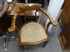 An old tub shaped desk chair having cane seat with spindle back
