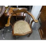 An old tub shaped desk chair having cane seat with spindle back