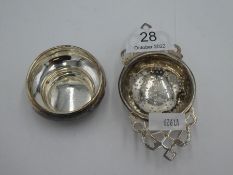 A silver tea strainer on a stand, having two decorative silver handles of pierced design. Hallmarked