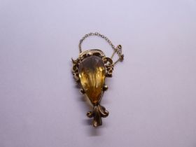 Antique yellow metal brooch with central pear shaped Citrine framed with a scrolling yellow metal mo