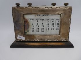 A silver mounted desk calendar on a wooden base. Hallmarked Birmingham 1913 W J Myatt and Co., 15cm