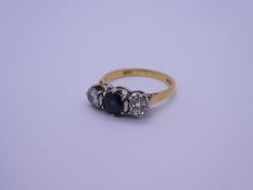 18ct yellow gold trilogy ring with central round cut sapphire flanked diamonds either side, London,
