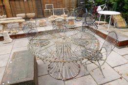 An ornate circular metalwork garden table with a set of six matching folding chairs