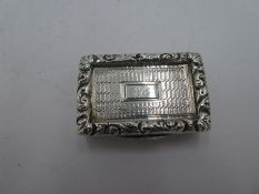 A silver Georgian vinaigrette having gilt decorative interior and repoussed, foliate lid with centra