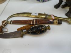 Two Eastern daggers (one having brass sheath) and one other leather covered dagger