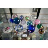 Two shelves of paperweights including a Mdina example