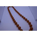 Vintage string of circular amber beads, each amber bead separated by a clear bead, 54g approx