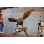 A large brass Eagle, perched on a log