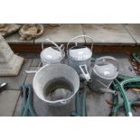 Three galvanised watering cans and bucket