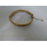 A 9ct yellow Gold bangle, with engraved pattern, safety chain AF, approx  6.5 cm in diameter, marked