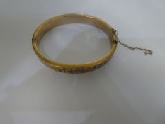 A 9ct yellow Gold bangle, with engraved pattern, safety chain AF, approx  6.5 cm in diameter, marked