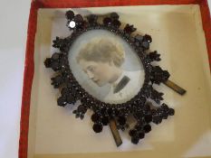 An antique miniature photo frame encrusted with circular garnet panels AF, framing a water colour of
