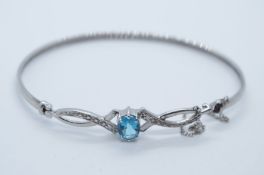 Pretty 9ct white gold bangle with fancy panel inset with diamond chips and oval mixed cut blue topaz