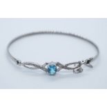 Pretty 9ct white gold bangle with fancy panel inset with diamond chips and oval mixed cut blue topaz