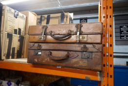Three vintage suitcases, two leather and a case of vintage clothing